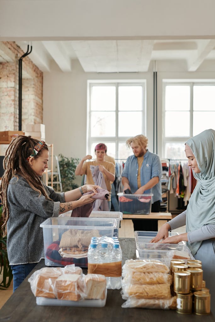 A diverse group of volunteers sorting clothes and food items at an indoor donation center for a non-profit